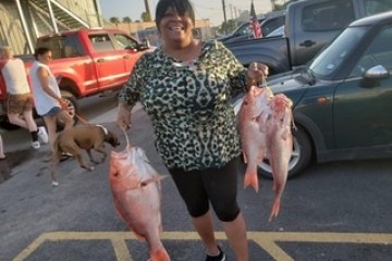 a person holding a fish in front of a car
