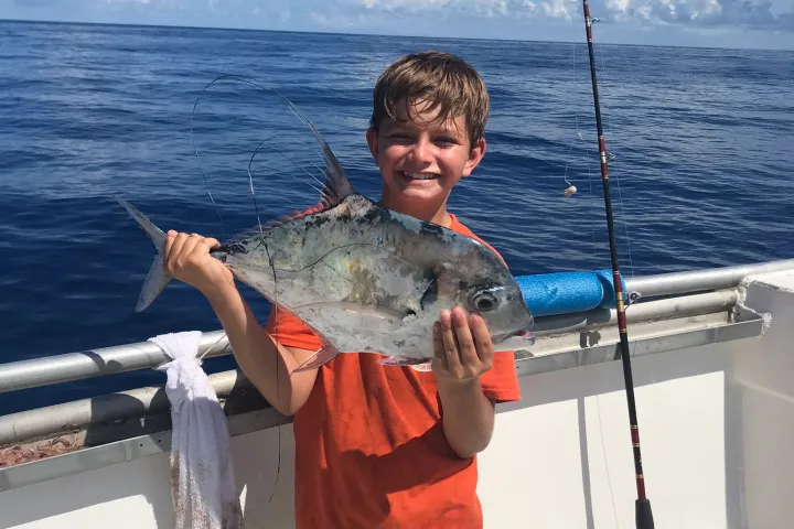 a young boy standing next to a body of water