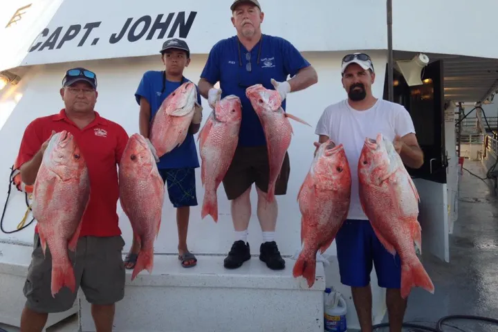 a group of people standing next to a man holding a fish