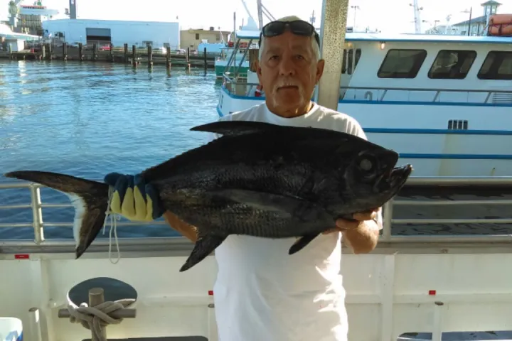 a man holding a fish on a boat in the water