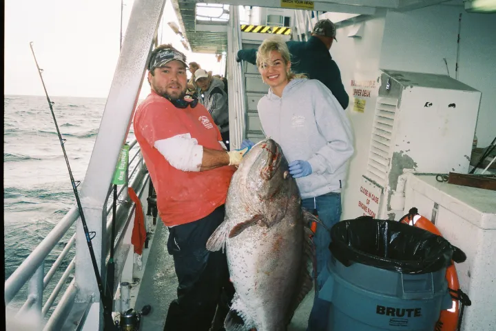 man and woman with big fish on boat