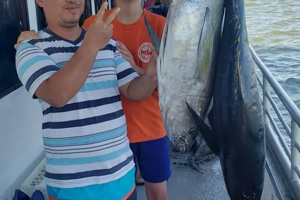 a person holding a fish on a boat posing for the camera
